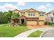 Charming tan two-story home featuring a brick-paved driveway, manicured lawn, and a spacious three-car garage at 3899 Mount Vernon Way, Kissimmee, FL 34741