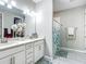 Bright bathroom featuring a double vanity with white cabinets and a shower with tile surround at 591 Lake Smart Blvd, Winter Haven, FL 33881