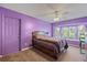 Bedroom with purple walls, a bay window, ceiling fan, and a wooden bed with storage drawers at 621 Rebecca Dr, St Cloud, FL 34769