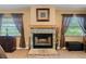Stone fireplace with a wooden mantle flanked by matching windows with brown curtains at 621 Rebecca Dr, St Cloud, FL 34769