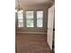 Living room featuring carpeted floors, wood blinds, three windows, and a three-light chandelier at 6957 Northwich Dr, Windermere, FL 34786