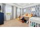 Well-lit bedroom boasts lots of natural light, stylish wallpaper, a crib, and plush carpeting at 7400 Estuary Lake Loop, Celebration, FL 34747