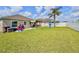 Large backyard with playground equipment, patio area, white fence, and a lush green lawn at 810 Jefferson Blvd, Haines City, FL 33844