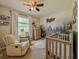 Comfortable Bedroom with a crib, glider chair, mural, and natural light from the window at 810 Jefferson Blvd, Haines City, FL 33844