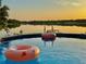 Relaxing above-ground pool overlooking a serene lake at sunset, complete with inflatable pool floats and palm trees at 822 S Breen Rd, Lake Wales, FL 33898