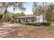 Exterior view of a charming single story home with columns, covered front porch, mature trees, and spacious front yard at 8310 Happy Trails, Kissimmee, FL 34747