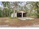 Detached two-car garage with open doors, showing an unfinished interior surrounded by trees and greenery at 8310 Happy Trails, Kissimmee, FL 34747