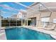 An enclosed pool area with seating, lounge chairs and a beautiful pool with an in-ground hot tub at 833 Brunello Dr, Davenport, FL 33897