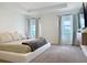 Serene main bedroom featuring a minimalist bed, neutral decor, and natural light from large windows at 895 Overpool Ave, Davenport, FL 33896