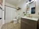 Bright bathroom featuring a shower/tub with curtain, modern vanity, and decorative mirror at 1025 Belvoir Dr, Kissimmee, FL 34744