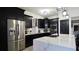 Contemporary kitchen featuring sleek black cabinets, stainless steel appliances, and a bright island with modern fixtures at 1025 Belvoir Dr, Kissimmee, FL 34744