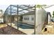 The screened in pool area of the home with lights above and a landscaped exterior at 1025 Belvoir Dr, Kissimmee, FL 34744