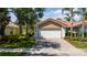 Features a two-car garage, red brick driveway, well-manicured lawn, and beautiful landscaping at 12041 Kajetan Ln, Orlando, FL 32827