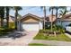Two-car garage with brick driveway, lush lawn, attractive landscaping, and solar panels on the roof at 12041 Kajetan Ln, Orlando, FL 32827