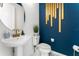 Stylish powder room featuring modern fixtures, a pedestal sink, and eye-catching gold wall decor at 14309 Lanikai Beach Dr, Orlando, FL 32827