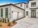 Striking modern home with a white facade, contrasting black trim, and a driveway leading to a two-car garage at 15121 Pendio Dr, Montverde, FL 34756