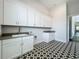 Well-appointed laundry room featuring ample white cabinetry, gray countertop, and black and white patterned tile flooring at 15121 Pendio Dr, Montverde, FL 34756