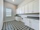 Bright laundry room with ample storage cabinets, a sink and stylish patterned floors at 15121 Pendio Dr, Montverde, FL 34756