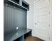 Functional mudroom featuring a custom gray built-in bench with storage and hooks near a white five-panel door at 15121 Pendio Dr, Montverde, FL 34756