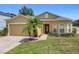 Charming single-story home featuring a well-manicured lawn, brick driveway, and a beautiful palm tree in the front yard at 15341 Groose Point Ln, Clermont, FL 34714