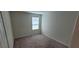 An empty bedroom with neutral carpeting and a single window for natural light at 1556 Aspen Ave, Davenport, FL 33837