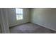 An empty bedroom with neutral carpeting, baseboards, and natural light from a window at 1556 Aspen Ave, Davenport, FL 33837