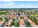 Expansive aerial view of a residential community featuring well-maintained homes with orange tiled roofs and lush landscaping at 16614 Lazy Breeze Loop, Clermont, FL 34714
