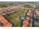 Aerial view showcases homes with orange tile roofs surrounding a community pool and green spaces at 16614 Lazy Breeze Loop, Clermont, FL 34714