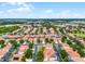 Expansive aerial view of a residential community featuring well-maintained homes with orange tiled roofs and lush landscaping at 16614 Lazy Breeze Loop, Clermont, FL 34714