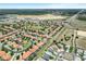 An aerial view shows a sprawling community with uniform terra cotta roofs near a commercial area and highway at 16614 Lazy Breeze Loop, Clermont, FL 34714