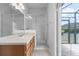Bathroom featuring a glass shower, light cabinets, and access to an outdoor screened patio at 16614 Lazy Breeze Loop, Clermont, FL 34714