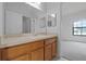 Bathroom showcasing a vanity with cabinets, a large mirror, and view into bedroom at 16614 Lazy Breeze Loop, Clermont, FL 34714