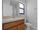 Bathroom features light cabinets, a sink with a mirror, and a toilet with a window at 16614 Lazy Breeze Loop, Clermont, FL 34714