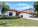 Charming single-story home showcasing a red tile roof, well-maintained lawn, and an attached two-car garage at 16614 Lazy Breeze Loop, Clermont, FL 34714