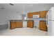 Bright kitchen with wooden cabinets, white appliances, and an open floor plan to the living room at 16614 Lazy Breeze Loop, Clermont, FL 34714