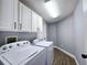 Laundry room with gray walls, tile floors, washer, dryer, and storage cabinets at 2312 Twickingham Ct, Clermont, FL 34711