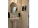 Bathroom with a pedestal sink, oval mirror, decorative art, and a doorway to a laundry area at 2495 Palm Tree Dr, Kissimmee, FL 34759