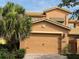 Two car garage with brick paved driveway and mature landscaping including a palm tree at 2495 Palm Tree Dr, Kissimmee, FL 34759