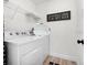 This laundry room features a white washer and dryer, open shelving, and decorative wall art at 252 Barbera Dr, Davenport, FL 33897