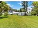 Expansive backyard featuring lush lawn, a garage, and additional storage buildings, all set against a serene sky at 2740 Barker Rd, St Cloud, FL 34771