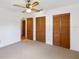 Bright bedroom featuring neutral carpet, ceiling fan, and wood closet doors at 2740 Barker Rd, St Cloud, FL 34771