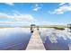 View of wooden dock leading to a boat house on calm lake with cloudy blue sky at 2740 Barker Rd, St Cloud, FL 34771