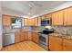 Kitchen featuring stainless steel appliances, tile backsplash, wood cabinets, and granite counters at 2740 Barker Rd, St Cloud, FL 34771