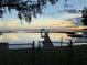 Picturesque waterfront scene featuring a dock, boat lift, and serene lake reflecting a colorful, dramatic sky at 2740 Barker Rd, St Cloud, FL 34771