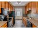 Efficient kitchen with wood cabinets and black appliances overlooking the living room at 4017 Dijon Dr # 4017K, Orlando, FL 32808