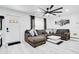 Modern living room with a large sectional sofa, wall-mounted TV, stylish ceiling fan, and sleek tile flooring at 416 E Seminole Ave, Lake Wales, FL 33853