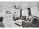 Modern living room with a large sectional sofa, wall-mounted TV, stylish ceiling fan, and sleek tile flooring at 416 E Seminole Ave, Lake Wales, FL 33853