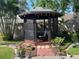 Screened gazebo, furnished with a table and chair, surrounded by beautiful plants and a brick walkway at 4926 Reginald Rd, Orlando, FL 32829