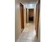 Hallway with neutral walls, white tile flooring, and wood trim around doors, offering a simple passageway at 4926 Reginald Rd, Orlando, FL 32829