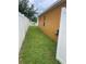 Side yard showing grass and the side of the home along with a white fence in the background at 513 Ronshelle Ave, Haines City, FL 33844